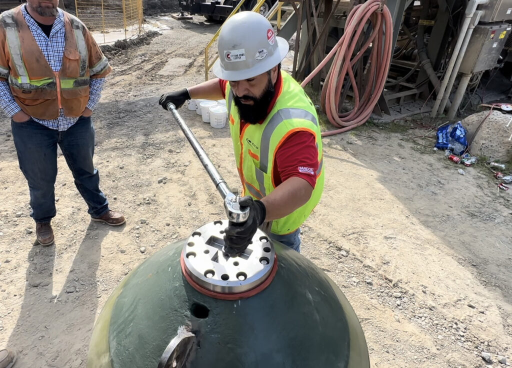 A man tightening the bolts on a crusher. 